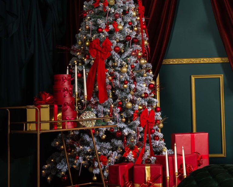 Red Muse holiday set at Hadaki Studios featuring a decorated Christmas tree with red and gold ornaments, wrapped red gifts, gold candles, and checkered floors—perfect for Christmas photoshoots in Toronto.
