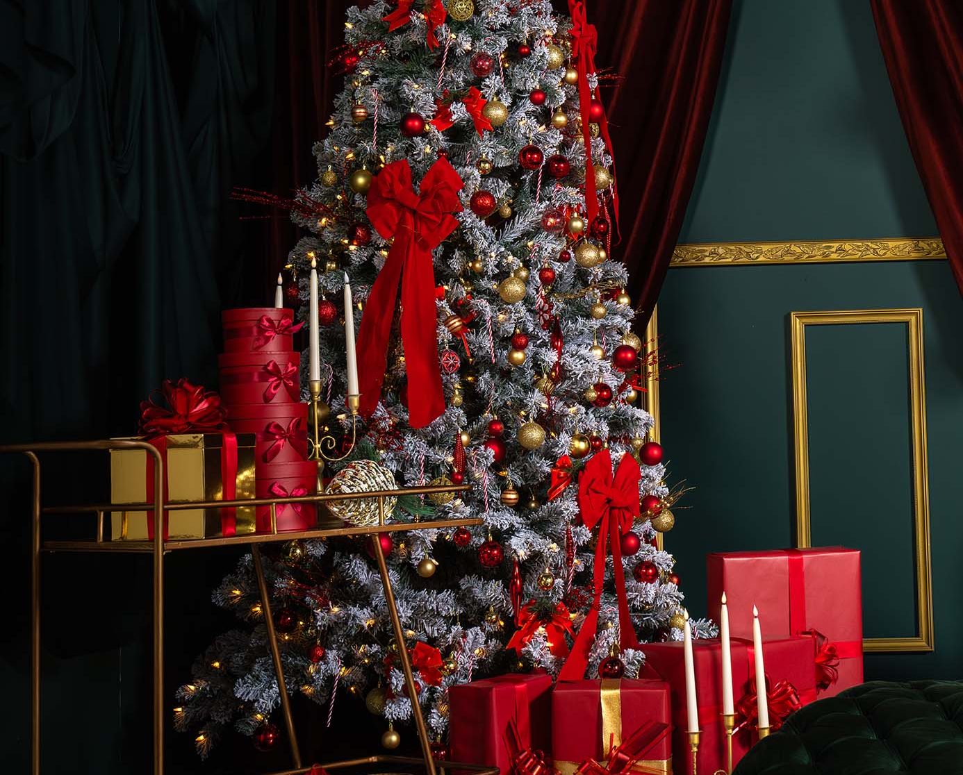 Red Muse holiday set at Hadaki Studios featuring a decorated Christmas tree with red and gold ornaments, wrapped red gifts, gold candles, and checkered floors—perfect for Christmas photoshoots in Toronto.