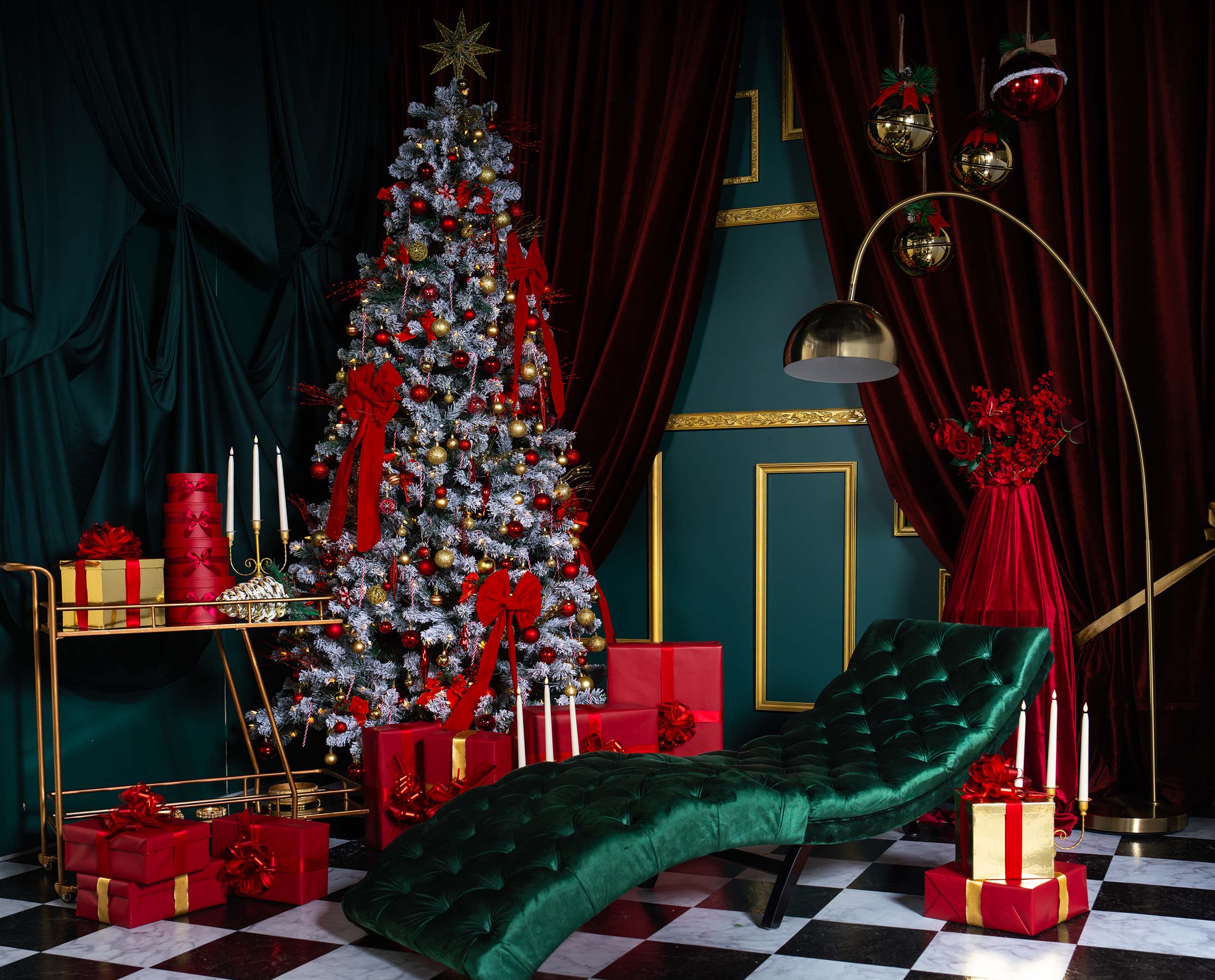 Red Muse holiday set at Hadaki Studios featuring deep red drapery, gold accents, a Christmas tree, festive gifts, and a luxe emerald chaise lounge. This is perfect for holiday photoshoots in Toronto.